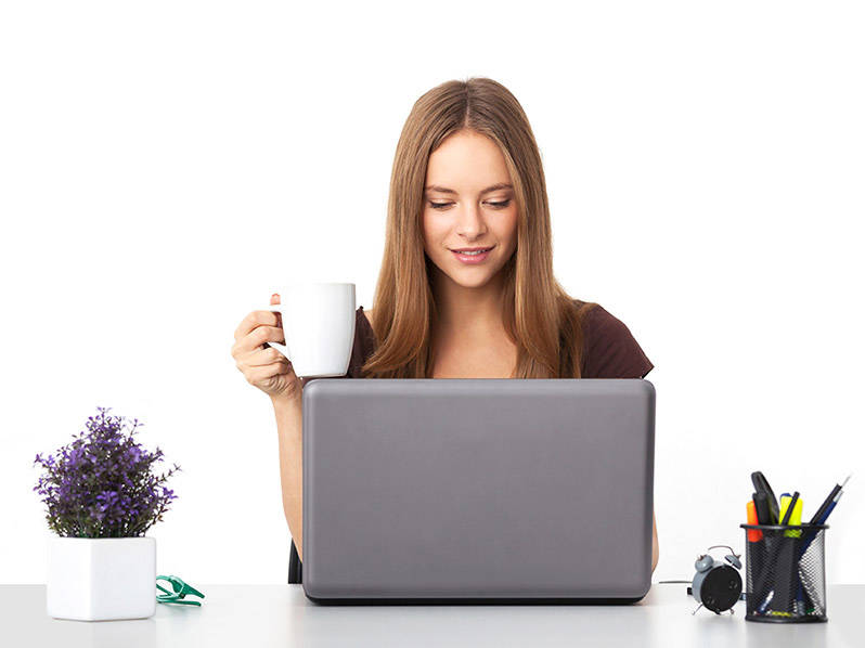 Perempuan di belakang komputer memegang cangkir kopi.