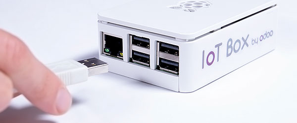 Una mano que conecta un cable USB a la caja IoT de Odoo.