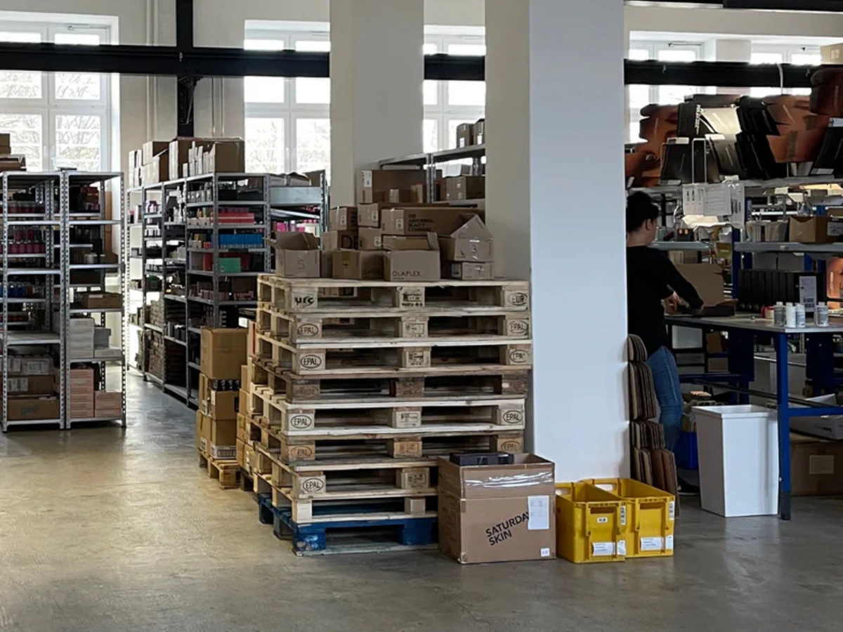 Inside the Purish GmbH warehouse showing organized inventory shelving and packing stations streamlined by Odoo ERP software.