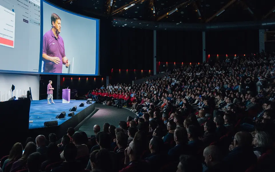 CEO on stage during an event giving the keynote in font of hundreds of people listening